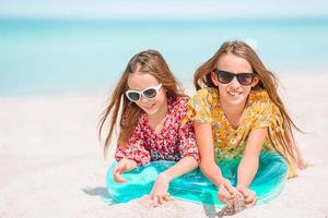 liten Lycklig rolig flickor ha en massa av roligt på tropisk strand spelar tillsammans. foto