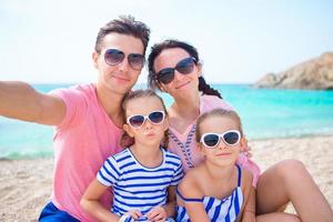 ung skön familj tar selfie på de strand foto