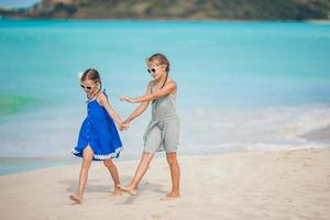 liten Lycklig barn ha en massa av roligt på tropisk strand spelar tillsammans foto