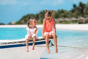 två liten Lycklig flickor ha en massa av roligt på tropisk strand spelar tillsammans foto