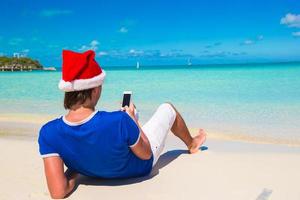 ung man i santa hatt på tropisk strand foto