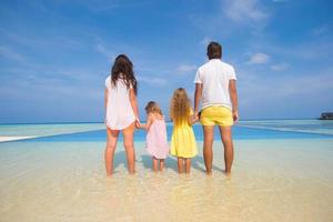 tillbaka se av skön familj på en strand under sommar semester foto