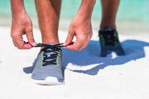 löpning man kvitt löpning sko skosnören på vit strand foto