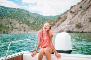liten flicka segling på båt i klar öppen hav foto