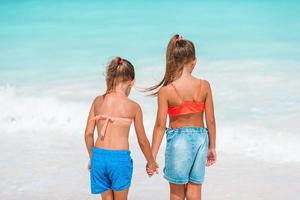 liten flickor har roligt på tropisk strand spelar tillsammans på grund vatten foto