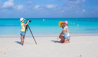 liten flicka framställning Foto av henne mamma och syster på de strand