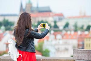 Lycklig ung urban kvinna i europeisk stad på de känd bro. caucasian turist gående i Prag, tjeck republik foto