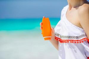 närbild solkräm flaska i kvinna händer på de strand foto