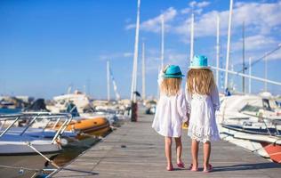 förtjusande liten flickor gående i en hamn på sommar dag foto