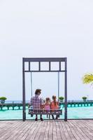 Lycklig far och hans förtjusande liten döttrar på tropisk strand har roligt foto