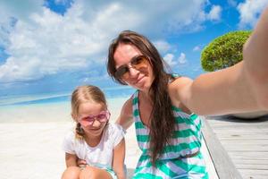 mor och liten flicka tar selfie på tropisk strand foto