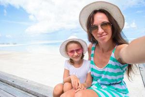 mor och liten flicka tar selfie på tropisk strand foto