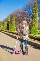 förtjusande liten flicka på de skoter i värma vår dag foto