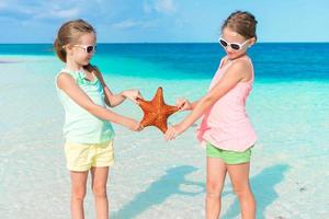 förtjusande liten flickor har roligt på de strand full av sjöstjärna på de sand foto