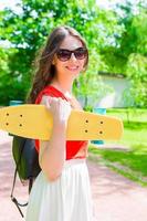 porträtt av Lycklig ung flicka med skateboard utomhus foto