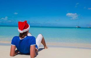 tillbaka se av ung man i santa hatt på tropisk strand foto