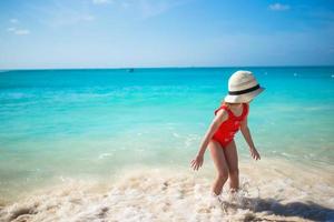 förtjusande liten flicka spelar i grund vatten på exotisk strand foto