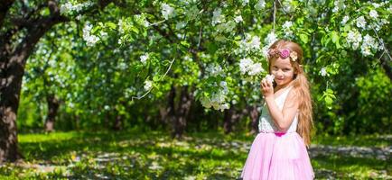 Lycklig liten förtjusande flicka i blomstrande äpple träd trädgård foto