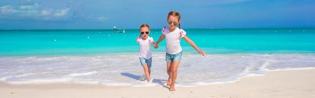 liten söt flickor njut av deras sommar semester på de strand foto