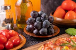 svarta druvor med tomater apelsinjuice och pizza foto