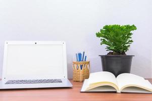 bärbar dator och blomma på skrivbordet foto