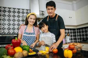 lycklig familj som skär grönsaker tillsammans i sitt kök foto