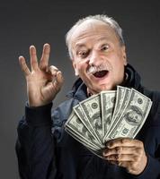 senior herre innehav en stack av pengar foto