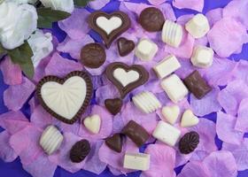 choklad bonbons på vit och rosa reste sig kronblad foto
