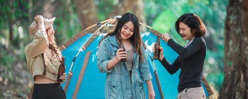 ung kvinnor heja på och dryck dryck främre av camping tält foto