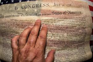 hand på deklaration av oberoende 4:e juli 1776 på USA flagga foto