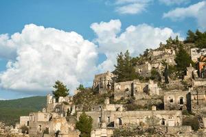 de ruiner av de övergiven grekisk stad av levissi nära de by av kajakoy i fethiye Kalkon, mot de bakgrund av stackmoln moln, de tragedi av krig. webbplats av de gammal stad av karmilissos foto