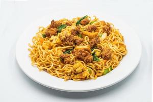 stek spaghetti med friterad kyckling nuggets på en vit tallrik isolerat på vit bakgrund. topp se asiatisk stek spaghetti stil. torr omedelbar nudel. asiatisk kryddad friterad curry omedelbar spaghetti. foto