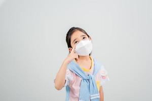 asiatisk liten barn flicka bär respirator mask till skydda coronavirus utbrott och pekande hand till tom bakgrund, ny virus covid-19 foto