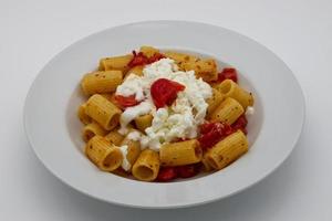 mezze maniche rigate, italiensk pasta, med körsbär tomater och stracciatella ost. foto
