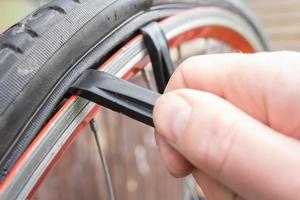 reparation en punkterad cykel hjul. cyklister hand tar bort de däck med en särskild spak verktyg. foto