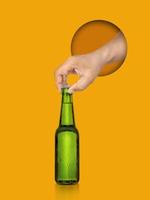 en man innehav öl flaska isolerat på gul bakgrund foto