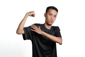 asiatisk man bär svart Träning t-shirt, som visar en stark hållning med Uppfostrad vapen och muskler. isolerat förbi vit bakgrund foto