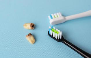 en modern elektrisk tandborste på en blå bakgrund Nästa till extraherad visdom tänder påverkade förbi karies. tand extraktion drift. hygien begrepp för dagligen vård. foto