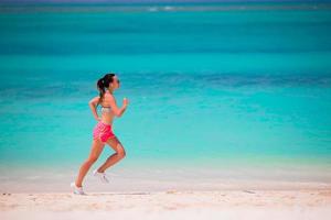 passa ung kvinna löpning längs tropisk strand i henne sportkläder foto