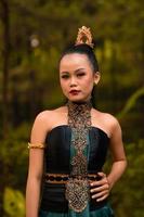 indonesiska kvinna med de grön klänning och smink på henne ansikte stående i främre av de djungel foto
