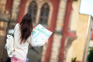 turist flicka med stadskarta gående på europeisk gator. resa caucasian kvinna med Karta utanför under högtider i Europa. foto