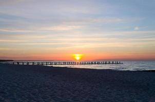på solnedgång, de groynes jut in i de hav. de Sol lyser på de baltic hav. landskap foto