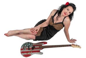 skön brunett kvinna i en svart klänning med en bas gitarr foto