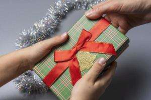 en låda med en jul gåva är passerade från hand till hand på en grå bakgrund foto