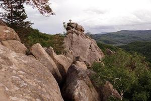 utsikt över klippor bland skog i bergen. dovbush stenar, regionen ivano-frankivsk. antikt grottkloster i fantastiska stenblock mitt i Karpaterna, ukraina foto