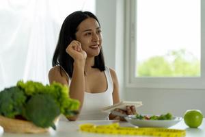 ung asiatisk kvinnor är förlorande vikt, välja till äta frukt och grönsaker för Bra hälsa. kvinnor är planera en friska diet till äta på varje måltid. diet begrepp foto