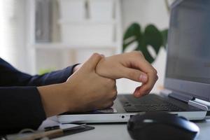 affärskvinna har en smärta i henne handled från använder sig av de dator för en lång tid. kontor syndrom foto
