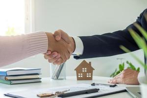 försäljning agenter och kunder skakning händer efter signering en kontrakt till köpa en ny hus eller lägenhet. inteckning, hyresvärd begrepp foto