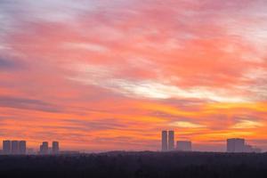 röd och orange himmel över stad parkera och torn foto