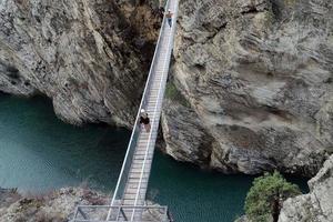 dagestan.russia.september 14, 2022.sulak canyon.view av en smal berg bro med turister korsning Det. foto